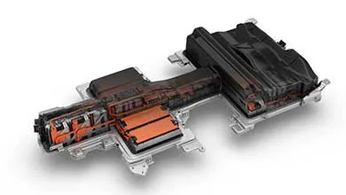 Cutaway view of a T-shaped electric vehicle battery pack, revealing orange battery cells and wiring within its black casing.