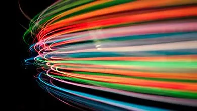 Glowing multicolored fiber optic cables arching against a black background.