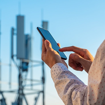 Person holding phone in front of 5G tower